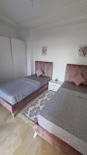 two beds sitting in a room with at Apparemment calm a Aouina in La Soukra