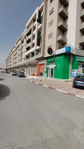 an empty street in front of a large building at Apparemment calm a Aouina in La Soukra