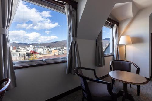 a room with a table and chairs and a window at Matsumoto Hotel Kagetsu in Matsumoto