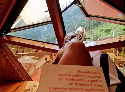 a person sitting in a window looking out at a view at Glamping Ibanazk in Ibagué