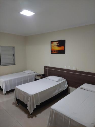 a room with two beds and a painting on the wall at Apoema Hotel in Cuiabá