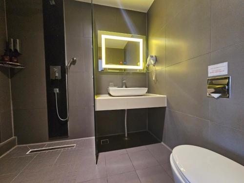 a bathroom with a sink and a toilet and a mirror at Sunland Hotel in Jeju