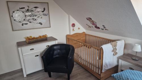 a baby room with a crib and a chair at Haus Herrenmühle Fewo OG 2 in Garding