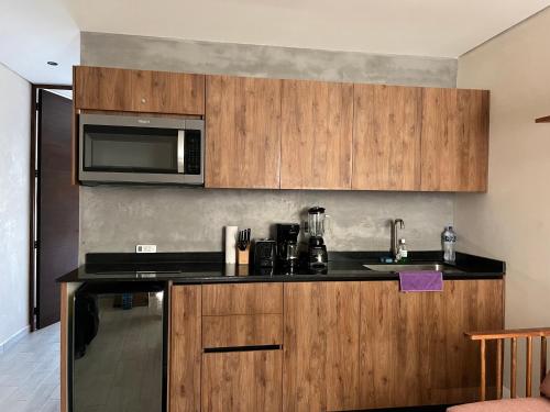 a kitchen with wooden cabinets and a microwave at JADE ZEN RESIDENCES - (35) in Tulum