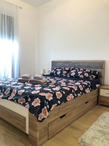 a bedroom with a bed with a floral comforter at Apartment TAJM in Trebinje