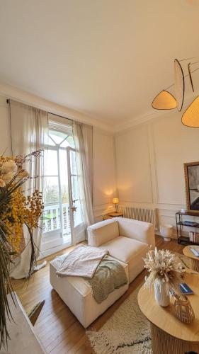 un salon avec un canapé et une grande fenêtre dans l'établissement La Belle Epoque, à Villers-sur-Mer