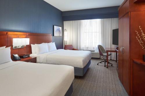 a hotel room with two beds and a desk at Courtyard by Marriott Waterloo St. Jacobs in Waterloo