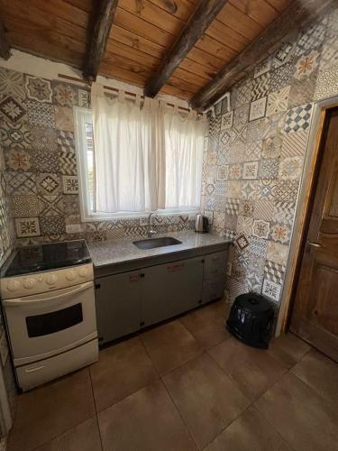 a kitchen with a sink and a stove and a window at Tu rincón la travesia in Las Compuertas