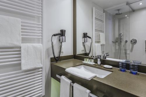 a bathroom with a sink and a large mirror at The Alex Hotel in Freiburg im Breisgau