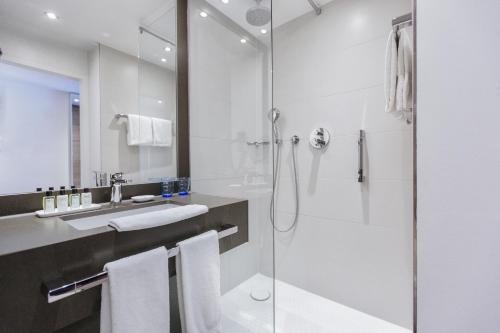 a white bathroom with a shower and a sink at The Alex Hotel in Freiburg im Breisgau