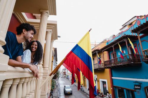 a man and woman looking out of a balcony with a flag at Kim in Cartagena de Indias
