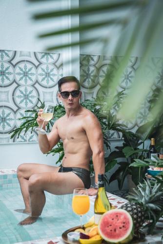 a man sitting in a swimming pool holding a drink at 海角瑞拉斯包棟民宿- Cape Relax Villa in Hengchun