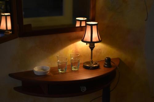 a table with a lamp and two glasses on it at Hotel CASA VICO in Ako
