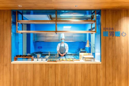 um chef atrás de um balcão na cozinha em Holiday Inn Express Liaocheng ETDZ by IHG em Liaocheng