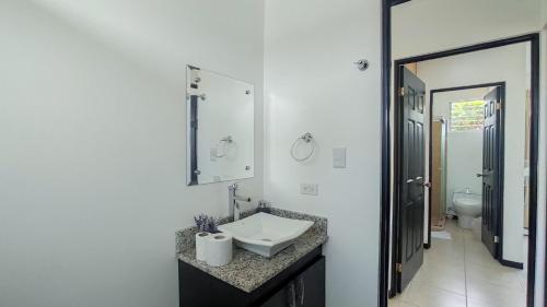 Baño blanco con lavabo y espejo en Beachside Bliss: Shared Pool, BBQ -Close to beach!, en Bejuco