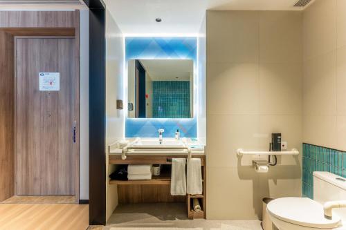 a bathroom with a sink and a toilet and a mirror at Holiday Inn Express Liaocheng ETDZ, an IHG Hotel in Liaocheng