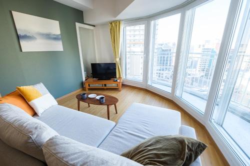a living room with a couch and large windows at AMS TOWER 1106 in Sapporo