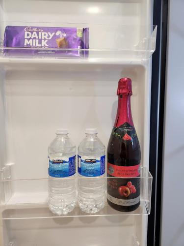a refrigerator with three bottles of water and a box of milk at The Serene Haven Modern 2 Queen Bed Full Apartment in St. Catharines