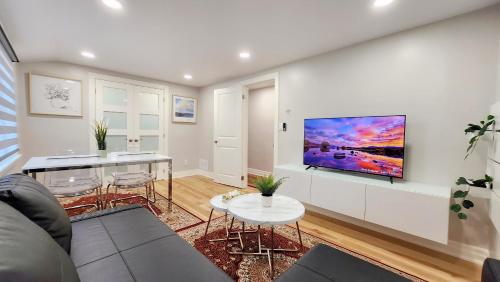 a living room with a couch and a tv on a wall at The Serene Haven Modern 2 Queen Bed Full Apartment in St. Catharines
