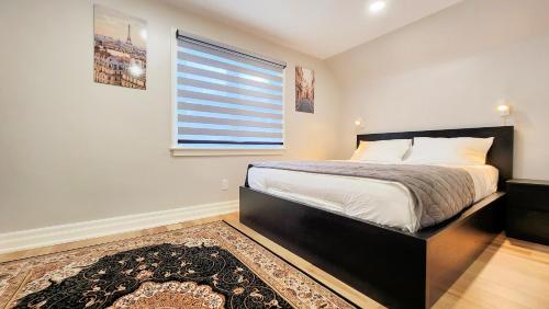 a bedroom with a bed with a window and a rug at The Serene Haven Modern 2 Queen Bed Full Apartment in St. Catharines