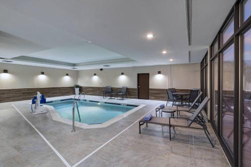 - une piscine avec des chaises et une table dans un bâtiment dans l'établissement Fairfield Inn & Suites by Marriott Colorado Springs East, à Colorado Springs