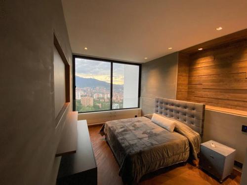 a bedroom with a bed and a large window at penthouse luxurytravelhome poblado in Medellín