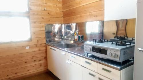 a kitchen with a stove and a sink at のんびれっじ　心和（ここわ）棟 in Shiozawa