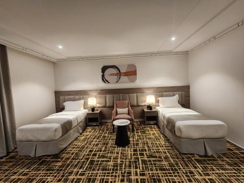 um quarto de hotel com duas camas e uma cadeira em فندق كنف - kanaf hotel em Ash Sharāʼi‘