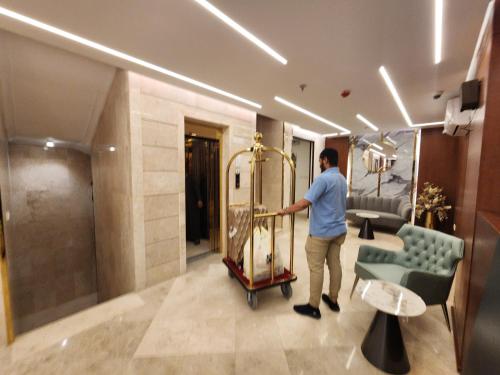 um homem a empurrar um carrinho de bagagem no átrio de um hotel em فندق كنف - kanaf hotel em Ash Sharāʼi‘