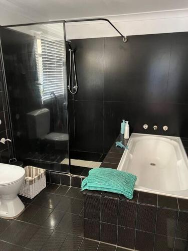 a bathroom with a bath tub and a toilet at Cosy Home in Heart of Subiaco in Perth
