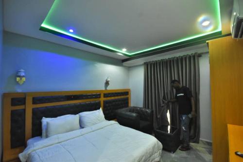 um homem em pé num quarto de hotel com uma cama em La Vista Imperial Hotel em Enugu