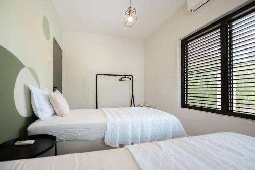 two beds in a white room with a window at VILLA Arte - just minutes from Mambo & Pietermaai in Willemstad