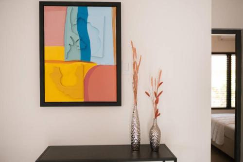 two vases on a table in a room with a painting at VILLA Arte - just minutes from Mambo & Pietermaai in Willemstad