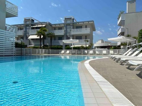 een groot zwembad met stoelen en een gebouw bij Luxury Apartment Centre. Pool. Beach and Shopping in Lido di Jesolo