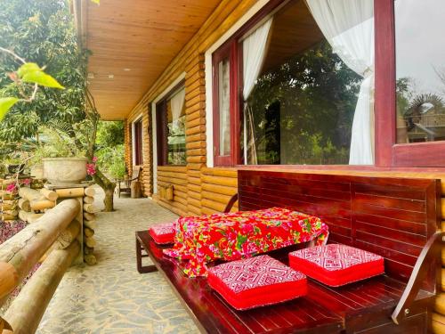 a porch with three red cushions on a bench at Pu Luong Jungle Lodge in Pu Luong