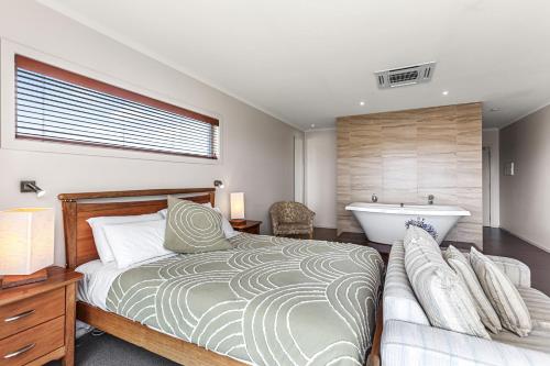 a bedroom with a bed and a bath tub at Captain's at the Bay in Apollo Bay