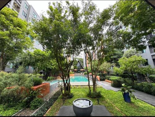a swimming pool in a yard with trees and a building at Cozy,convenient,shopping area in Chiang Mai