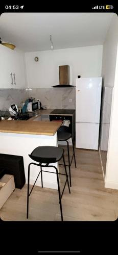 Il comprend une cuisine équipée de chaises, d'une table et d'un réfrigérateur. dans l'établissement Appartement moderne cosy, à Rosny-sous-Bois