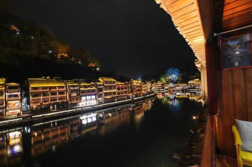 a view of a river at night with buildings at Fenghuang Ancient Town Lazy Cat Riverside Inn in Fenghuang