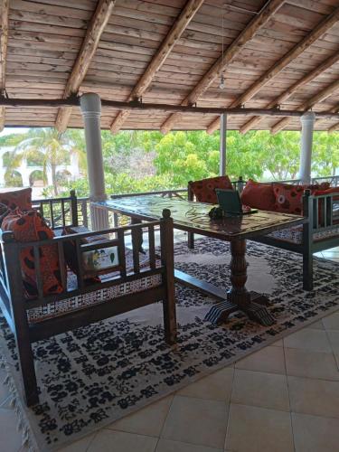 eine Terrasse mit einem Tisch und Stühlen sowie einem Laptop darauf in der Unterkunft Mkuu House in Malindi