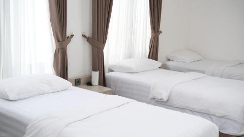 drie bedden in een kamer met witte lakens bij Villa Fumida in Cilama