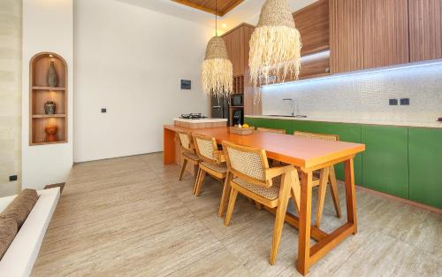 a kitchen with a wooden table and chairs at Dandelion Villas Pandawa by Nagisa Bali in Badung