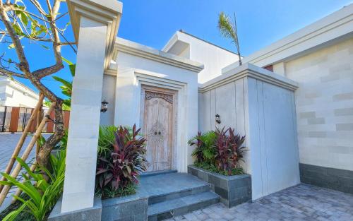 a white house with a door and some plants at Dandelion Villas Pandawa by Nagisa Bali in Badung