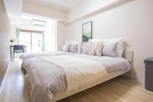 a large white bedroom with a large bed with white sheets at Walk to Ikebukuro Station. SoL3 in Tokyo