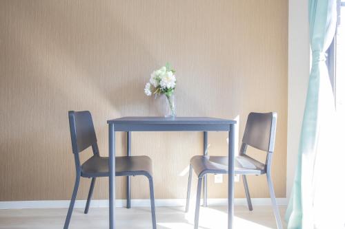 a blue table with two chairs and a vase of flowers at Walk to Ikebukuro Station. SoL3 in Tokyo