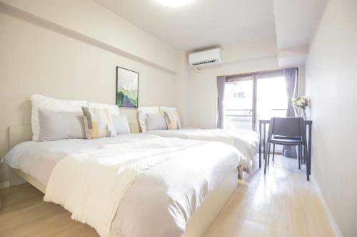 a white bedroom with two beds and a table at Walk to Ikebukuro Station. SYo in Tokyo