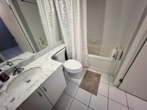 a white bathroom with a toilet and a sink at Downtown Toronto Cozy Suite in Toronto