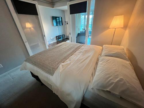 a large white bed in a bedroom with a lamp at Downtown Toronto Cozy Suite in Toronto