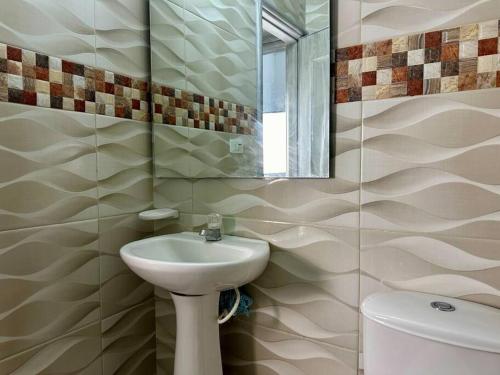 a bathroom with a sink and a mirror and a toilet at Acogedor apartamento Rodadero Santa Marta con vista al Lago in Santa Marta
