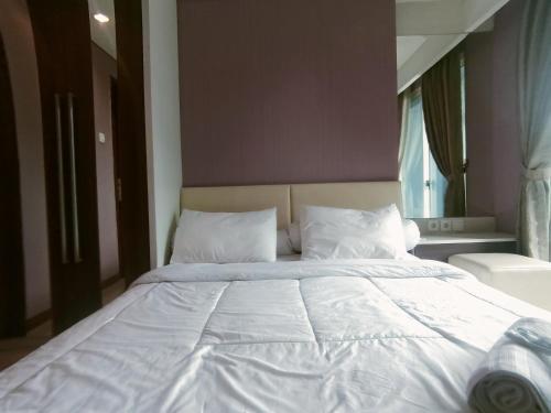 a bed with white sheets and pillows in a bedroom at eL Royale Apartment by Faris Property in Bandung